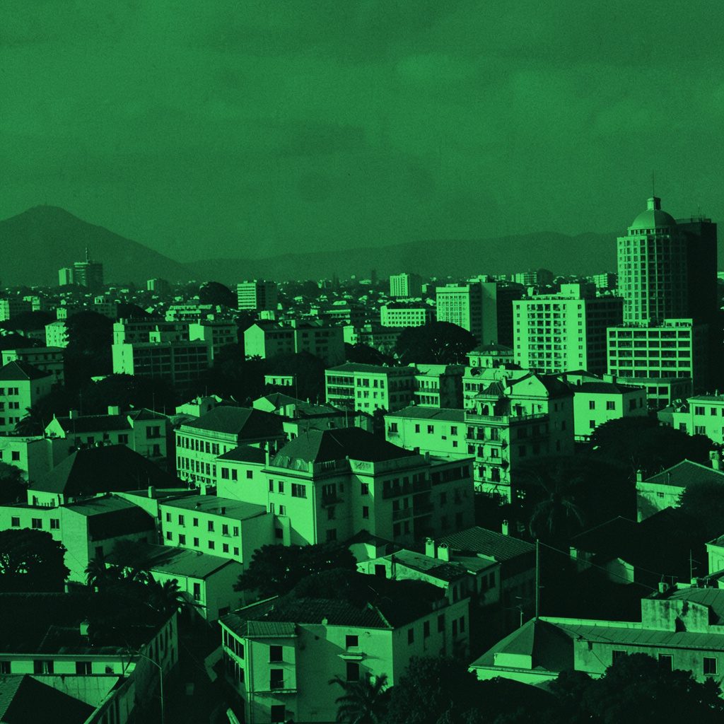 Two-tone duotone photograph of a hazy city skyline at dusk, rendered in soft sage green and warm white tones, evoking urban media and architecture.